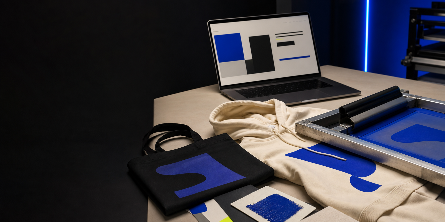 Textildruckrahmen, bedruckte Textilien und Laptop in einem dunklen Kreativstudio